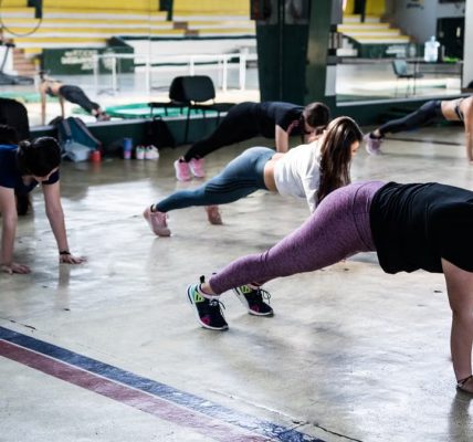 Group of women doing push-ups in a gym reflecting in a mirror.